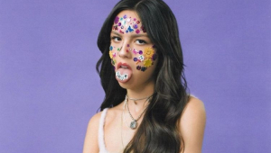 Capa do álbum de Olivia Rodrigo, onde ela aparece com várias figurinhas no rosto