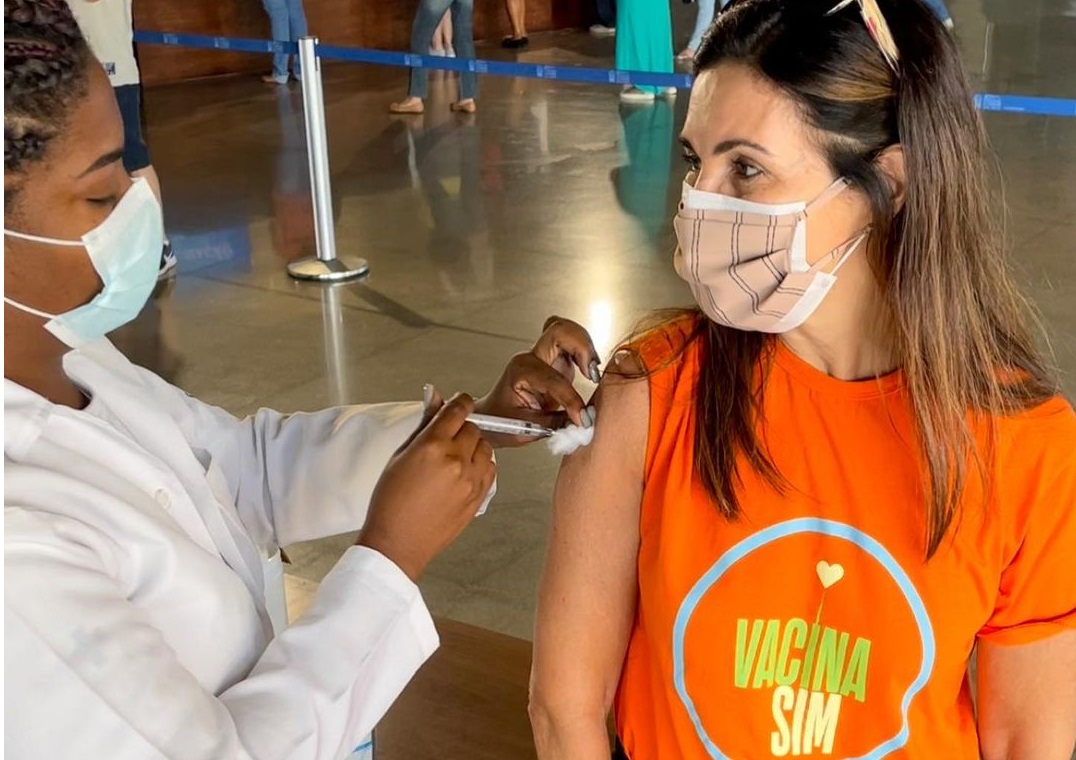 Fátima bernardes de camisa laranja recebendo vacina