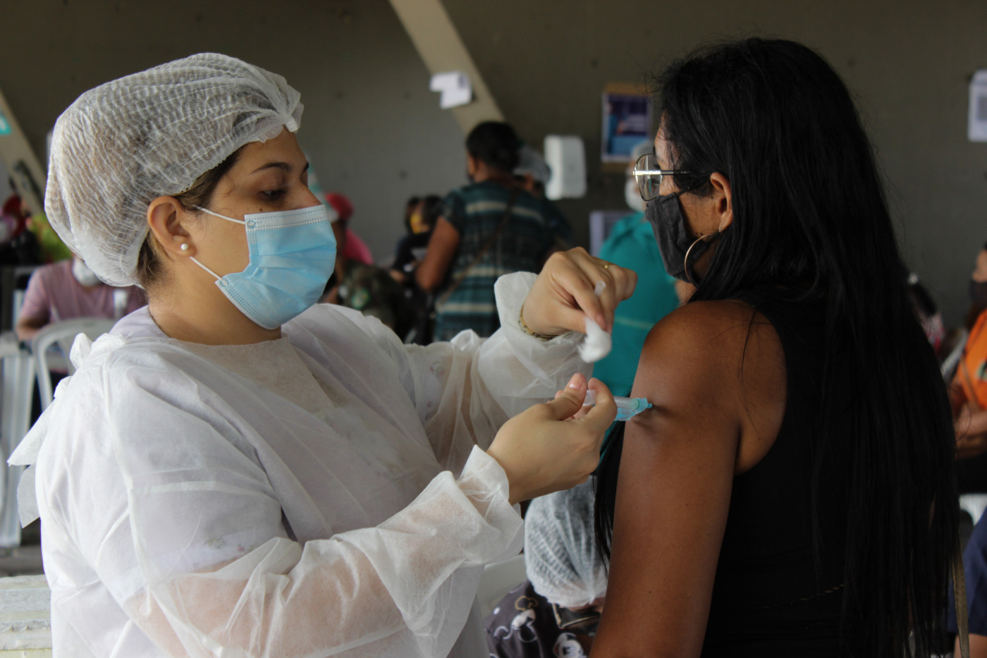 Enfermeira aplicando a vacina em uma mulher no Amazonas