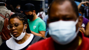 Na Avenida Paulista, mulher negra usa máscara no queixo; imagem mostra outras pessoas ao redor, todas com máscara