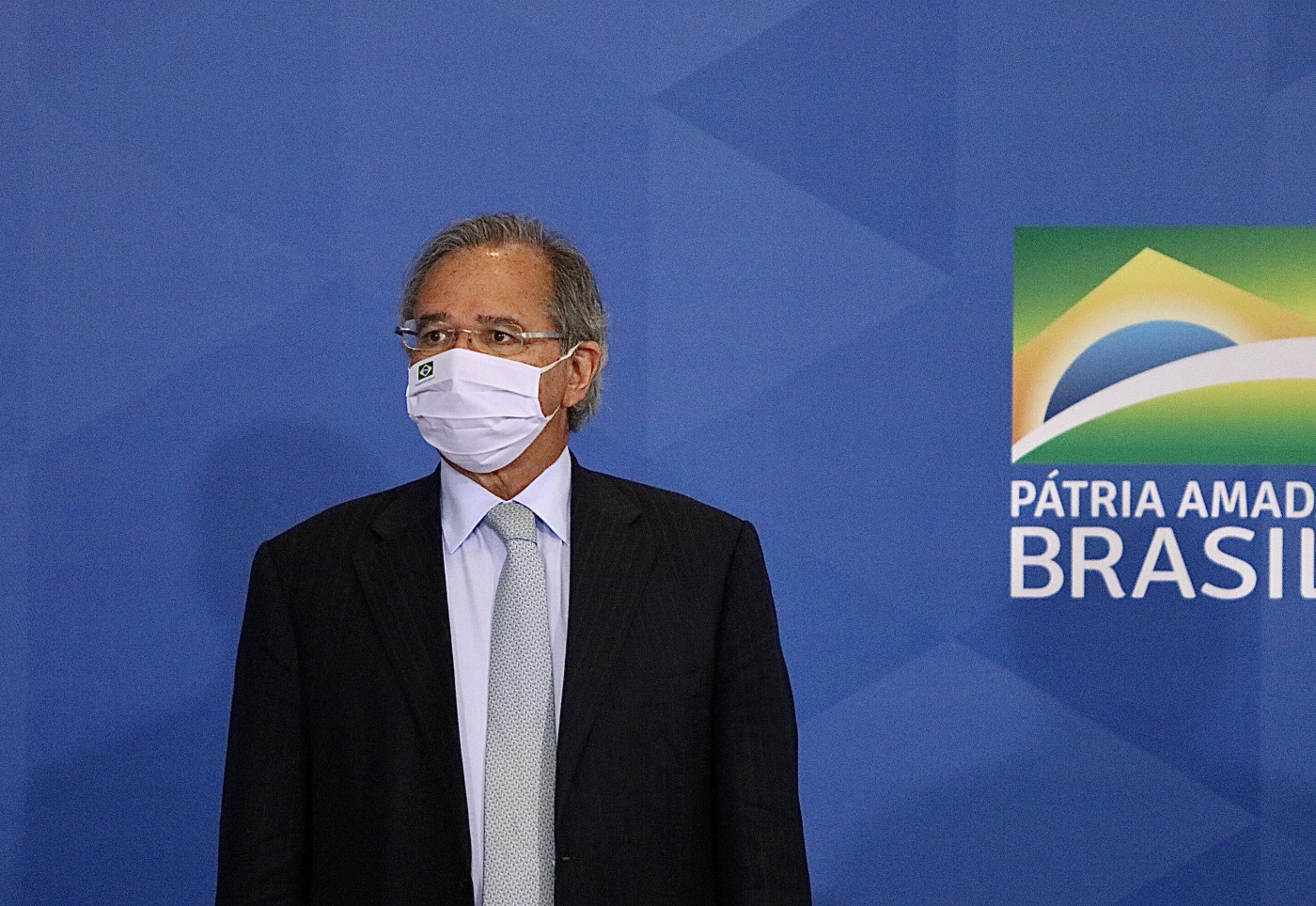 O ministro da Economia, Paulo Guedes, na frente do slogan do governo Bolsonaro: 'Pátria Amada Brasil'