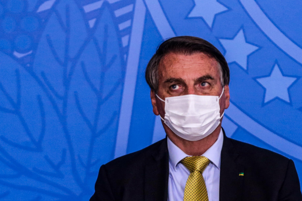 O presidente da república, Jair Bolsonaro, usa terno preto, gravata verde e camisa e máscara branca