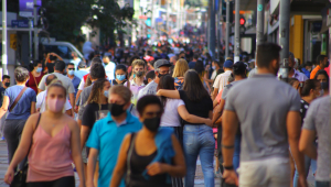 Pessoas andando na rua usando máscara