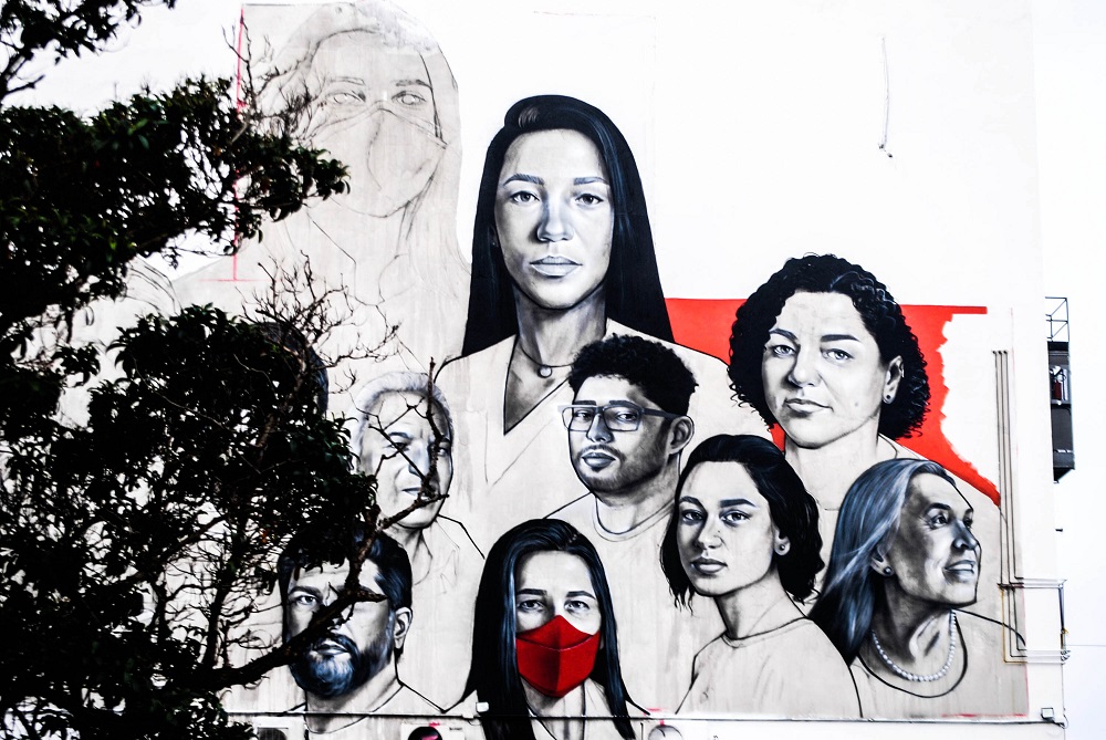 Mural ainda inacabado, pintado na lateral de hospital, mostra os rostos de nove profissionais da saúde