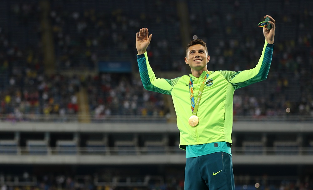 Thiago Braz, do salto com cara, levanta os braços e exibe medalha de ouro no peito no estádio