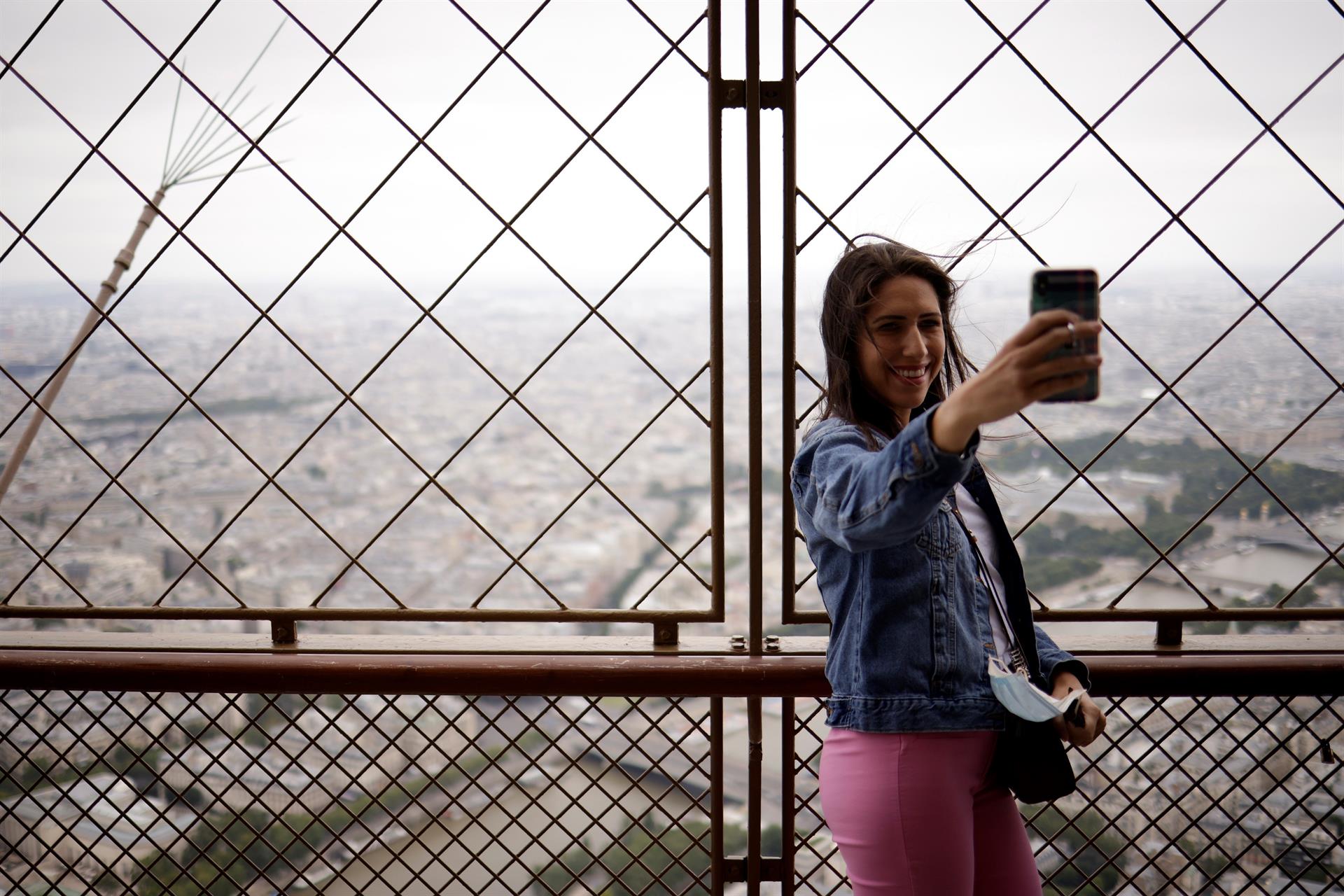 Mulher tirando selfie no topo da torre eiffel