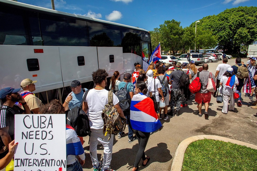 Com bandeiras de Cuba e cartazes, cubanos-americanos formam fila para entrar em ônibus rumo a Washington D.C.