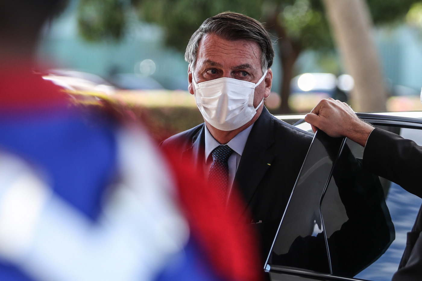 Usando terno preto e máscara branca, Bolsonaro sai de automóvel