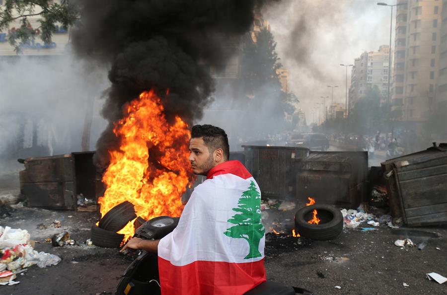 homem na frente de fogo durante protesto