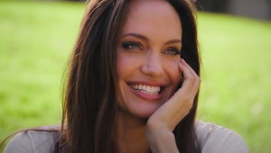 A atriz Angelina Jolie sorrindo com a mão no queixo