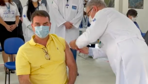 O senador Flávio Bolsonaro recebendo a primeira dose da vacina contra a Covid-19 pelo ministro Marcelo Queiroga