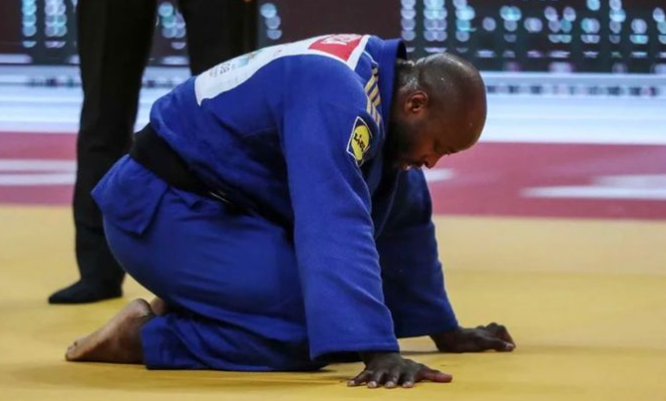 Jorge Fonseca se debruça no tatame com um kimono azul escuro