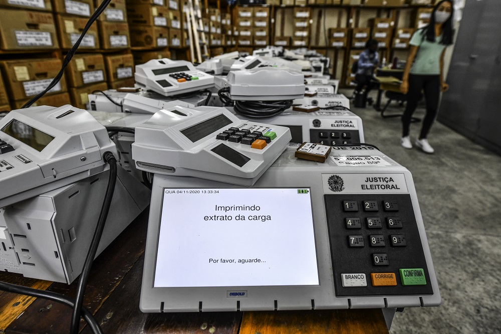 Sala com mesa cheia de urnas eletrônicas que seriam usadas nas eleições