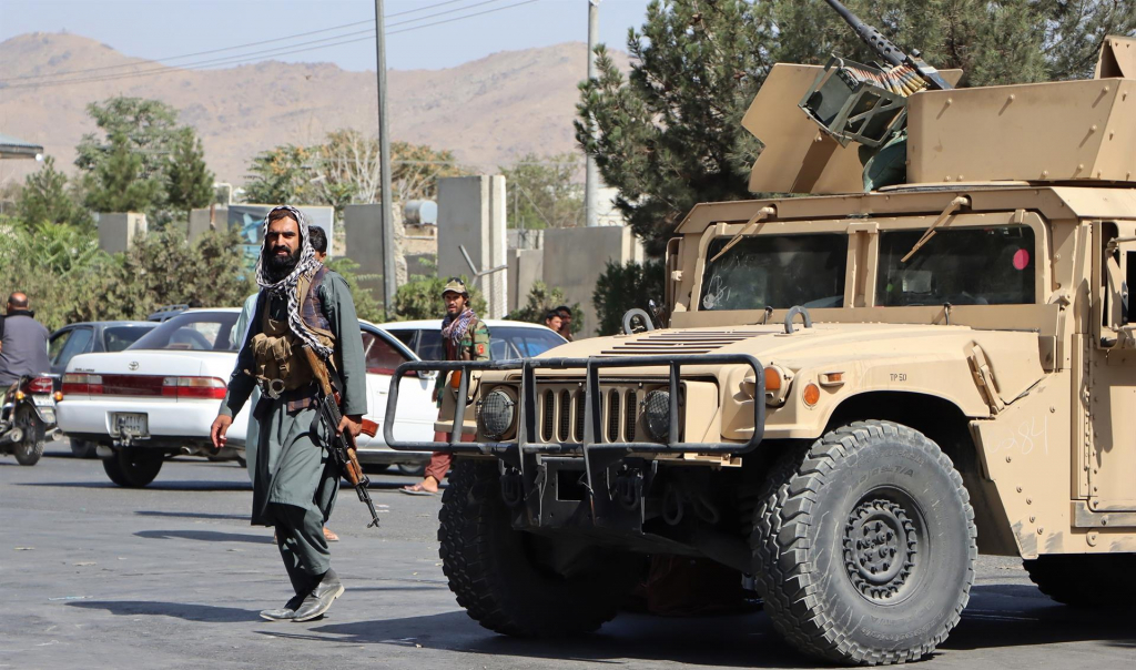 Soldado talibã andando na rua com arma em punho