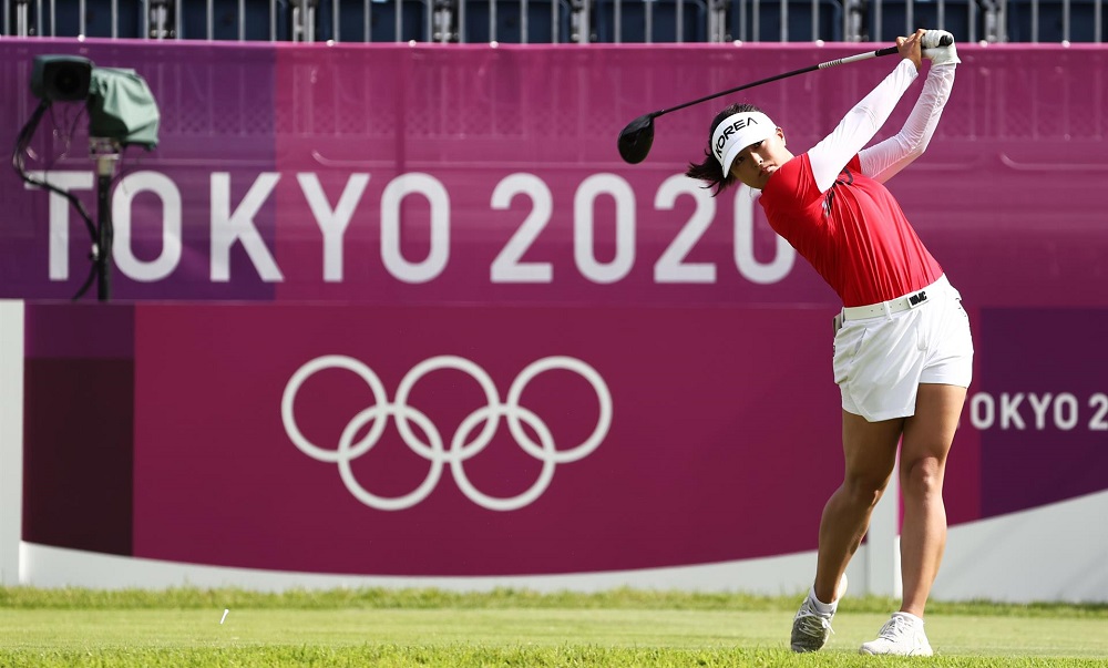 A golfista sul-coreana Koh Jin prepara um arremesso com um banner de Tóquio 2020 ao fundo
