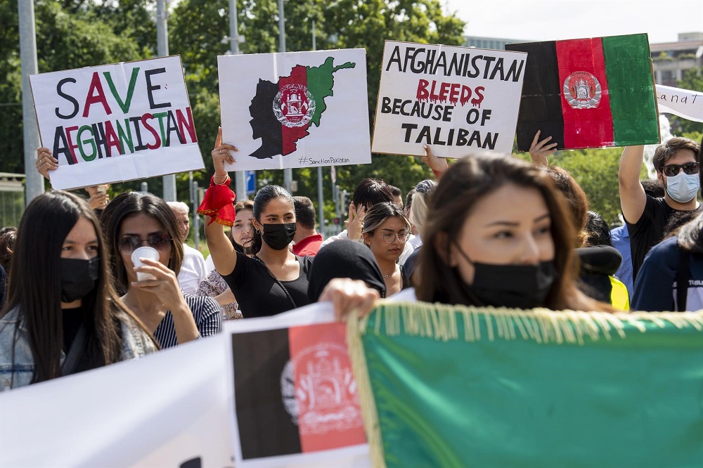 Mulheres, todas usando máscara, protestam com cartazes contra o Talibã