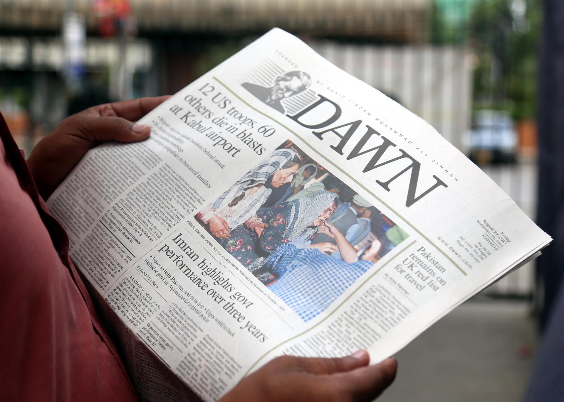 Pessoa lendo jornal com manchete mostrando ataques no afeganistão