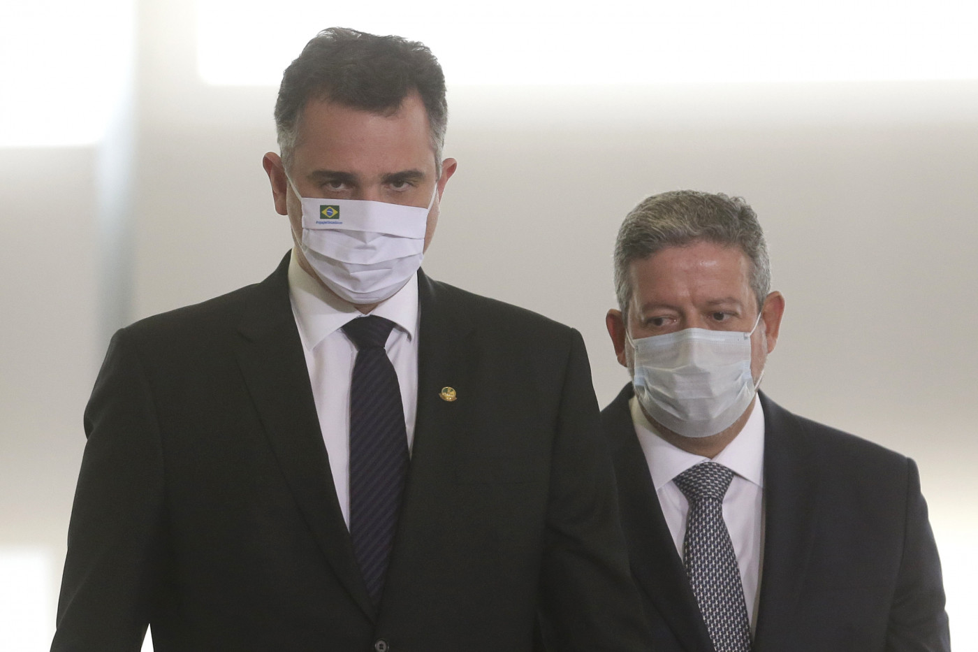 Trajados socialmente, Rodrigo Pacheco (à esquerda) e Arthur Lira (um pouco atrás do senador) caminham no Congresso