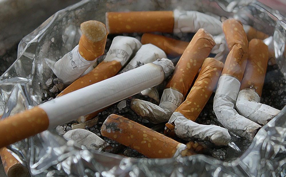Cinzeiro com um cigarro aceso e outros dez apagados, além de cinzas