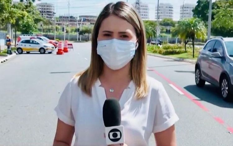 Repórter Cristina Mayumi na rua com o microfone da Globo