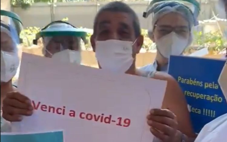 Zeca Pagodinho com os profissionais do hospital segurando uma folha