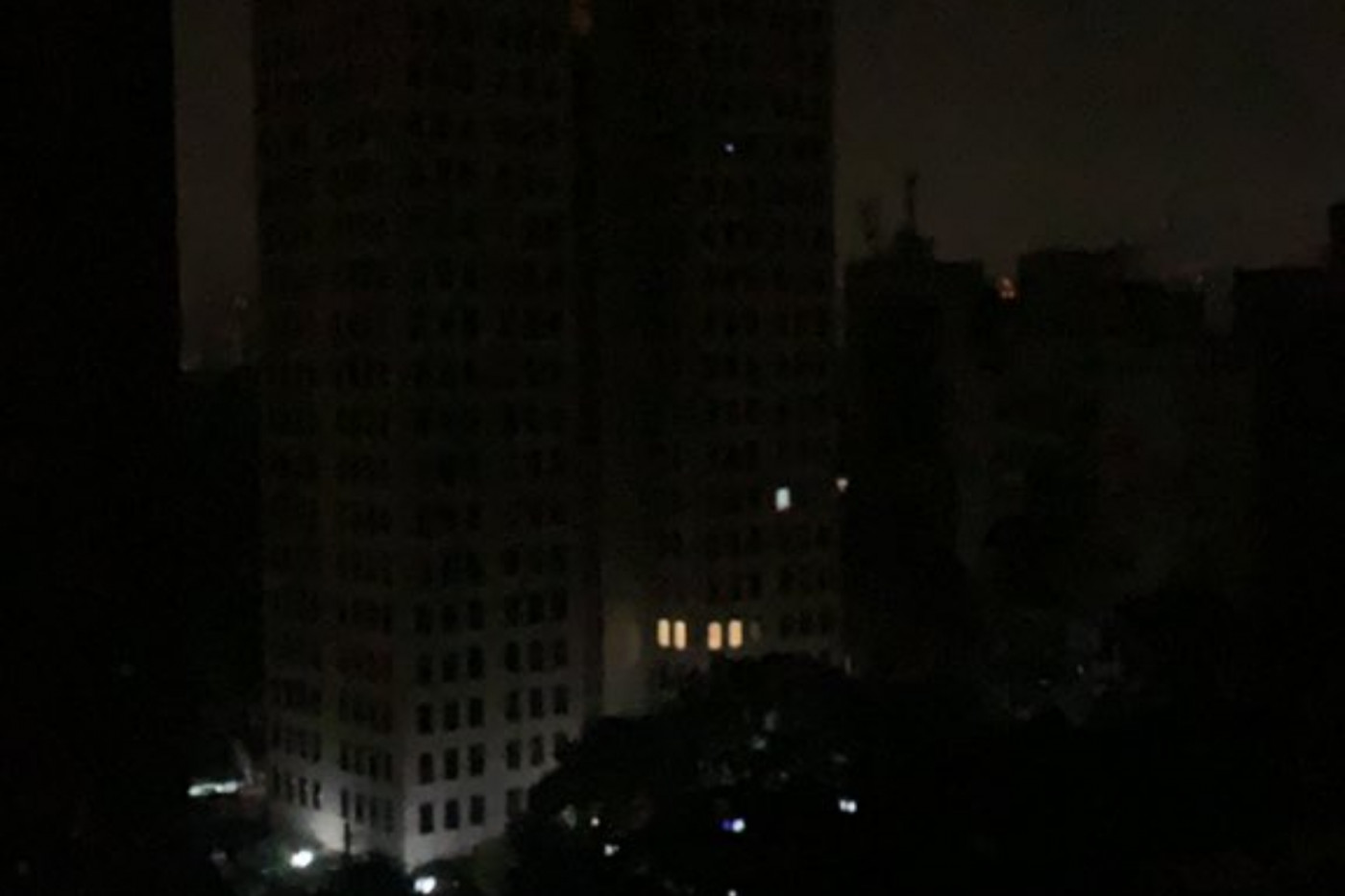 Vista de uma janela de predios e casas sem luz em São Paulo