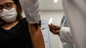 Profissional da saúde aplica vacina em uma mulher