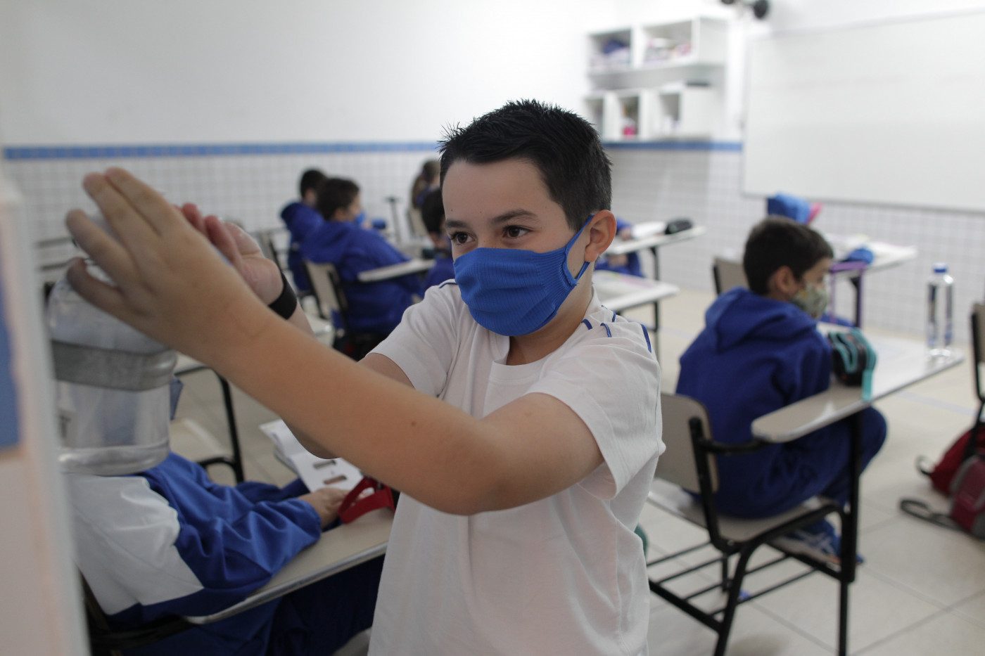 Menino usa máscara de proteção na escola e pega álcool gel