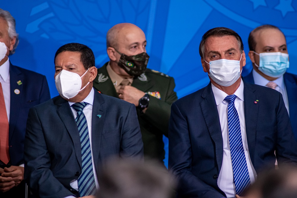 Sentados na bancada da frente durante posso de Ciro Nogueira, Hamilton Mourão, à esquerda, e Jair Bolsonaro, ambos de máscara e trajes sociais, sentam lado a lado, mas não se olham