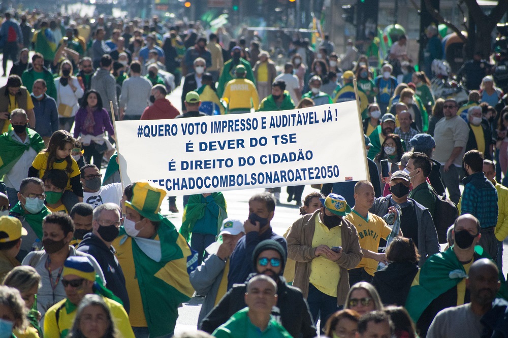Centenas de pessoas, a maioria usando camisa amarela, protesta em favor de Jair Boslonaro; uma faixa pede voto impresso e diz que está 