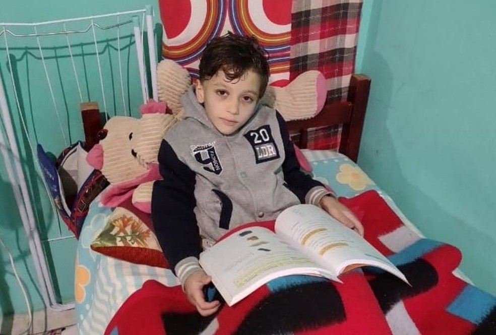menino miguel sentado lendo um livro