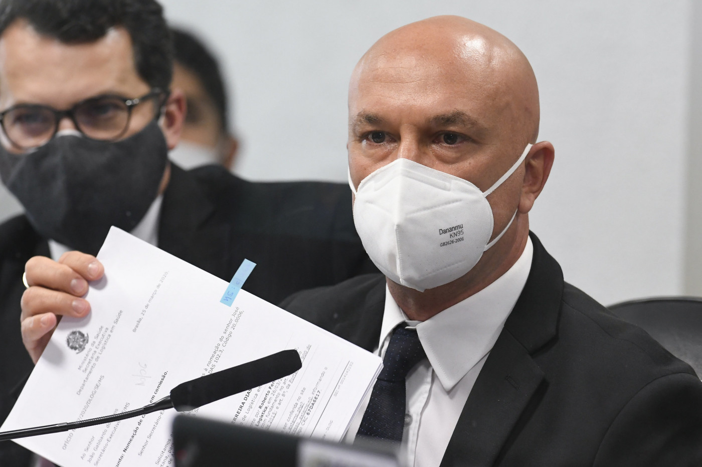 Homem de máscara exibe lista de documentos