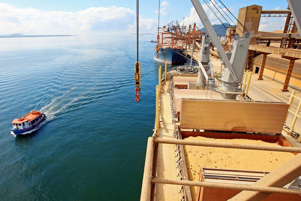 Porto de Paranaguá, um barco andando no mar e uma estrutura de metal ao lado