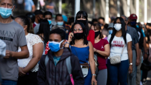 Pessoas com máscara caminham por uma rua da Venezuela