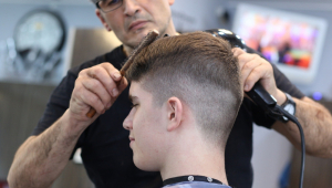 Homem corta cabelo de cliente em um salão de beleza
