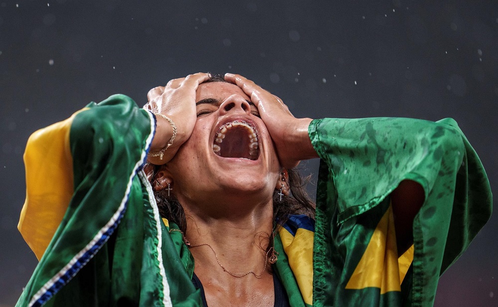 Com a bandeira do Brasil amarrada nas costas, Jardênia Felix coloca as nãos na cabeça e solta o grito após vencer prova nos 400 m T2