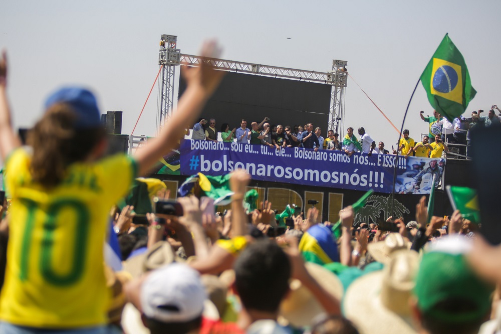Do alto de um palanque, rodeado de dezenas de aliados, jair Bolsonaro discursa para uma multidão de amarelo na Esplanada dos Ministérios