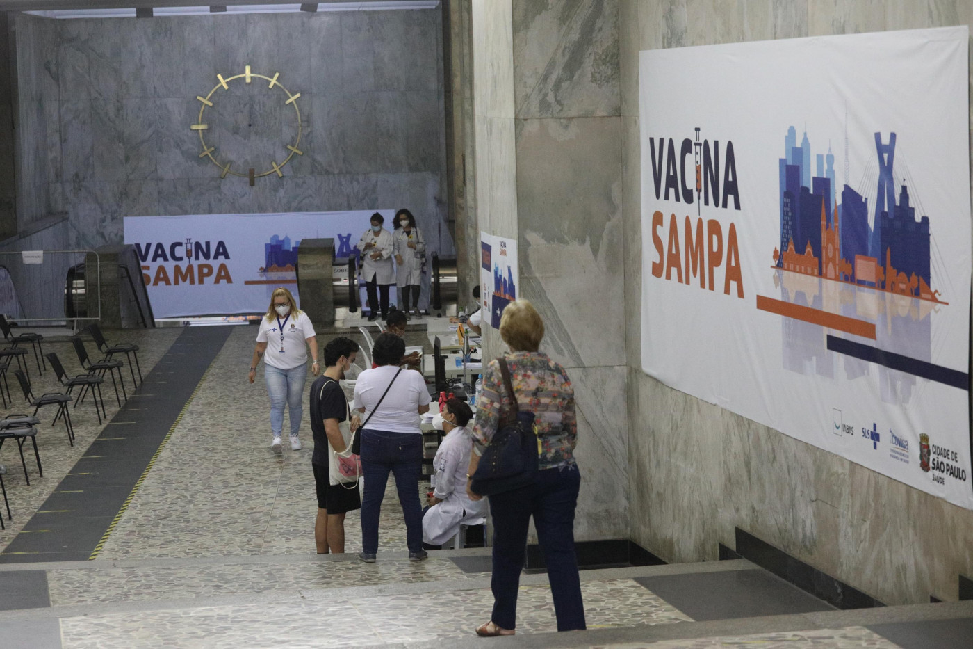 Pessoas na fila do Mega posto de vacinação contra a Covid-19 na Galeria Prestes Maia em São Paulo