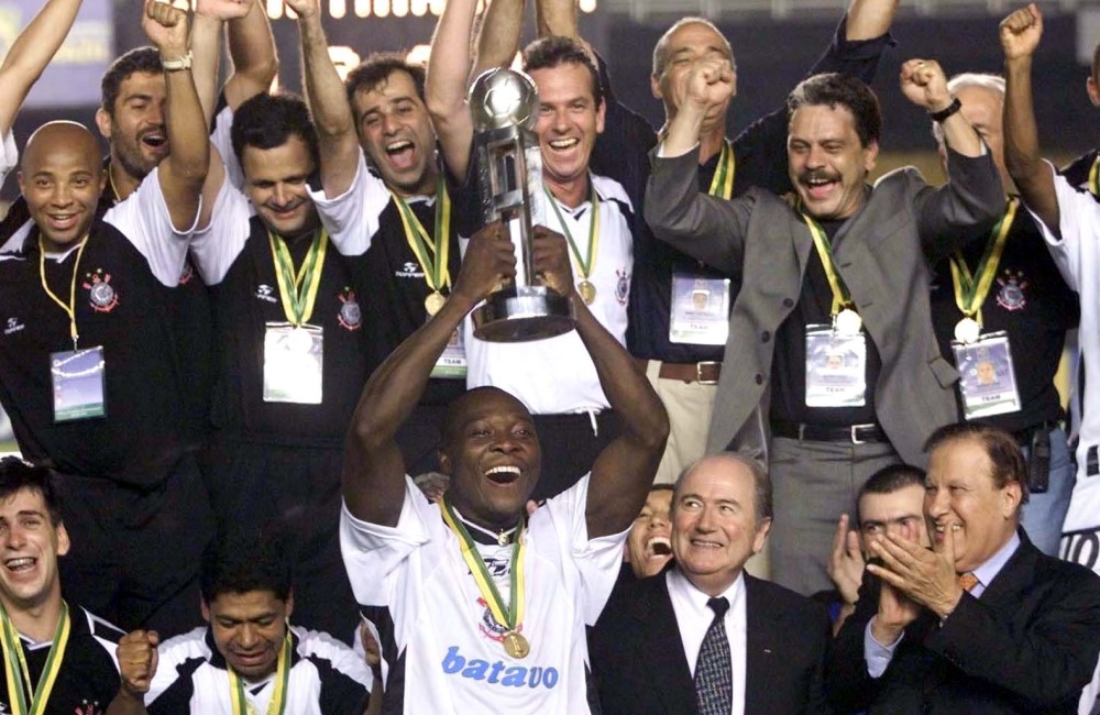 Cercado por jogadores, dirigentes e membros da comissão técnica do Corinthians, Rincón levanta o troféu do Mundial de 2000