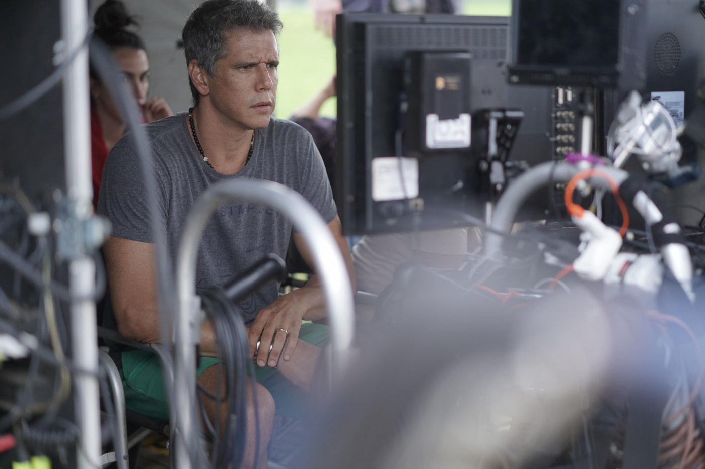 Márcio Garcia sentado olhando para o horizonte durante gravações do filme 'Reação em Cadeia'