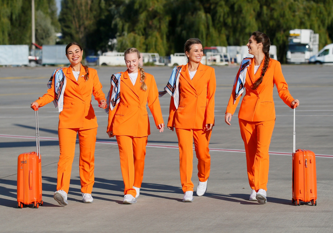quatro comissárias de bordo vestidas de laranja