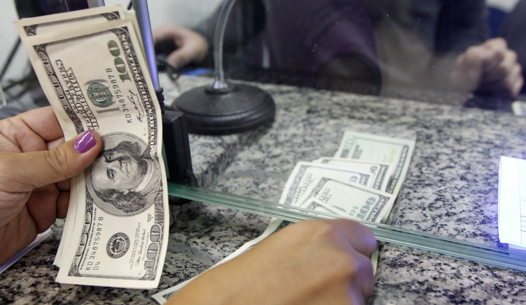 Mulher conta notas de dólar no guichê da casa de câmbio