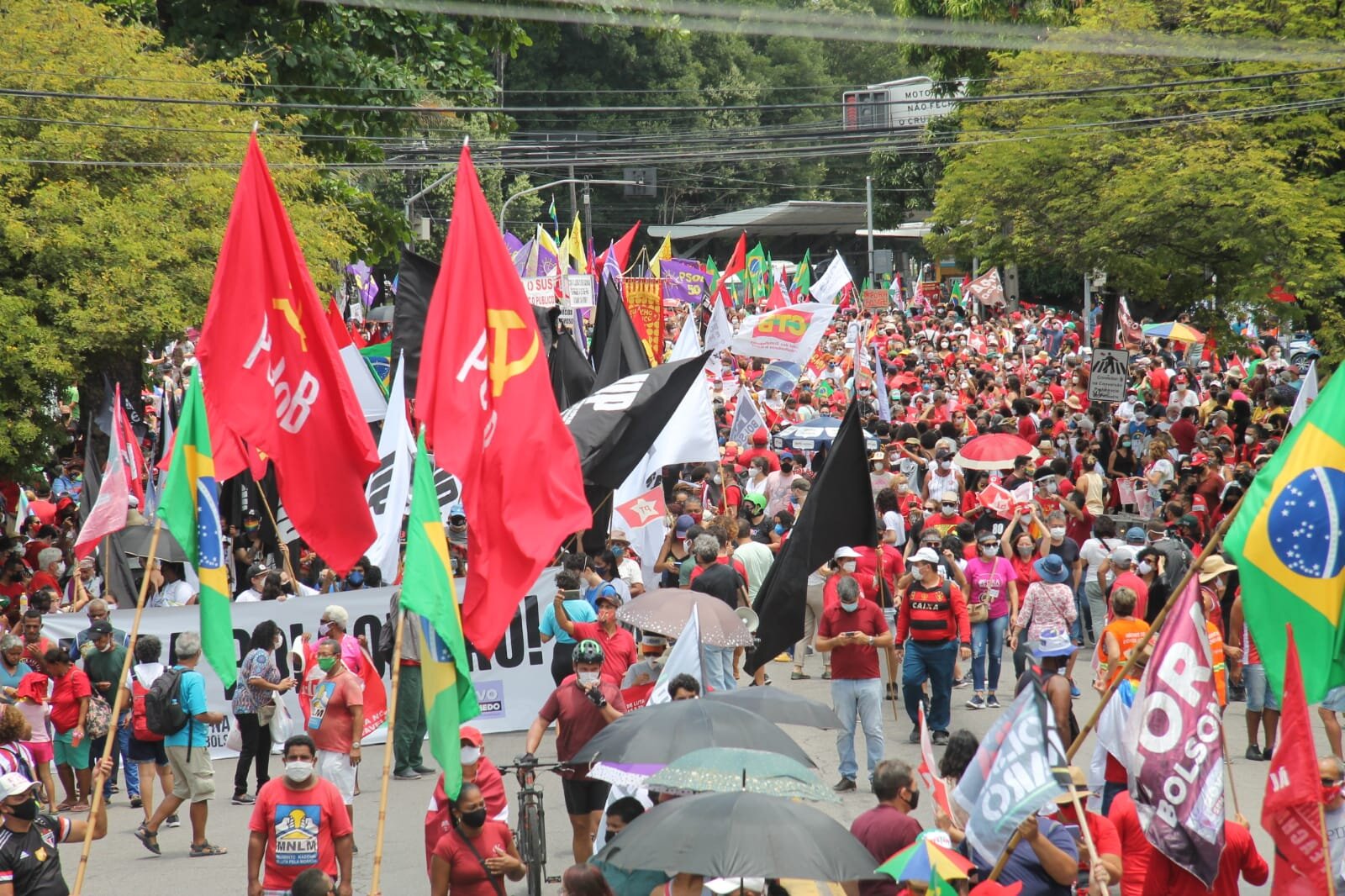 Grupo de pessoas com bandeiras vermelhas, camisetas vermelhas e bandeiras do Brasil reunidas em uma manifestação