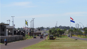 Fronteira entre Brasil e Paraguai, com duas ruas dividas por um canteiro central, com a bandeira de cada país em sua respectiva via