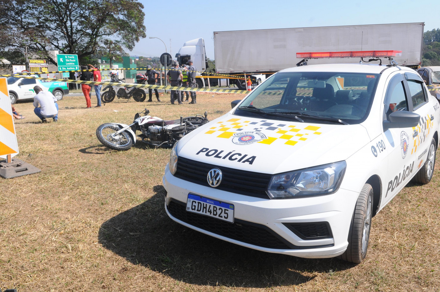 Carro da polícia militar ao lado de moto caída