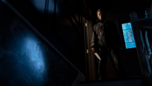 Cena do filme "Halloween Kills": com um facão na mão e a máscara característica cobrindo o rosto, o vlão Michael Myer olha do alto de uma escada, aparentemente em um porão escuro