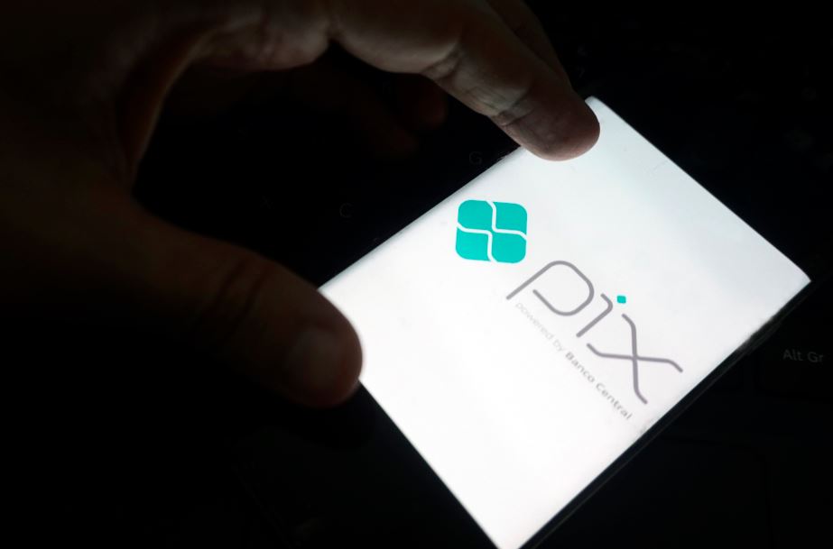 Mão segura um celular que exibe o símbolo do Pix