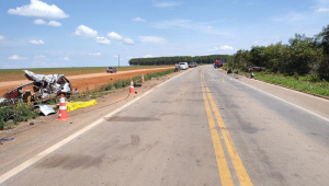 Imagem de uma estrada,c om horizonte ao fundo, um veículo totalmente destruído em um dos canteiros e outros dois mais à frente