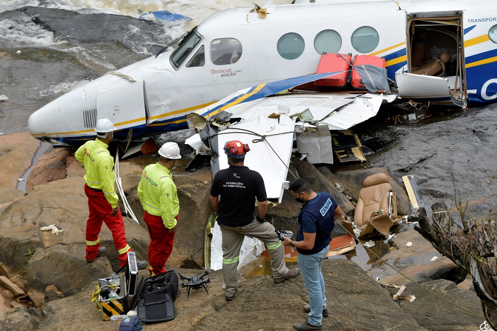 Policias e outras autoridades checam os destroços do avião