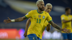 De braços abertos, Neymar comemora gol vestido com a camisa amarela e o shortts azul da seleção brasileira